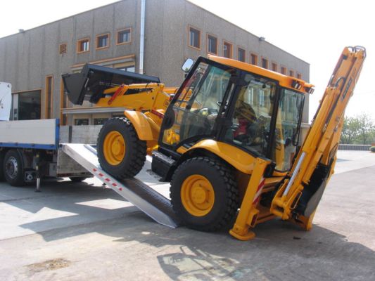 Digger loading on tipper truck using ramps 